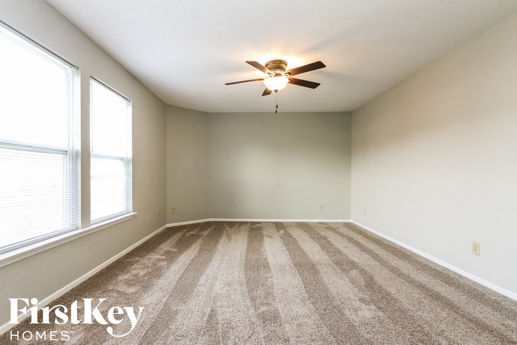 an empty living room with carpet and a ceiling fan