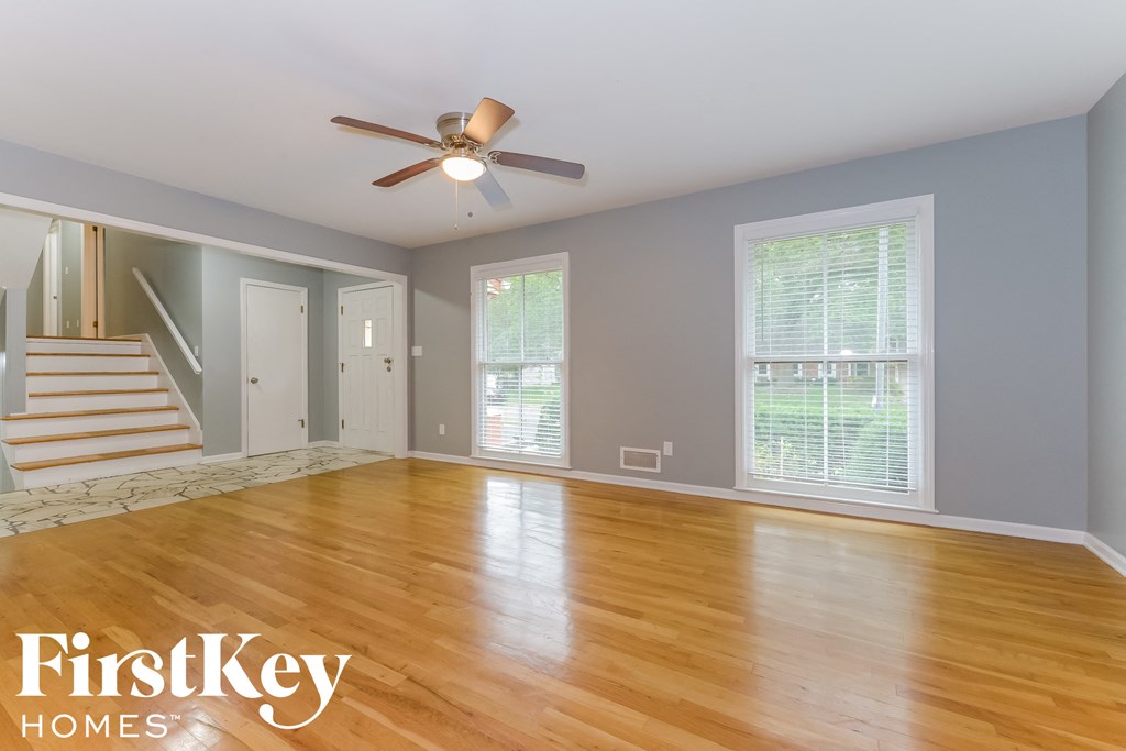 an empty living room with wood floors and a ceiling fan