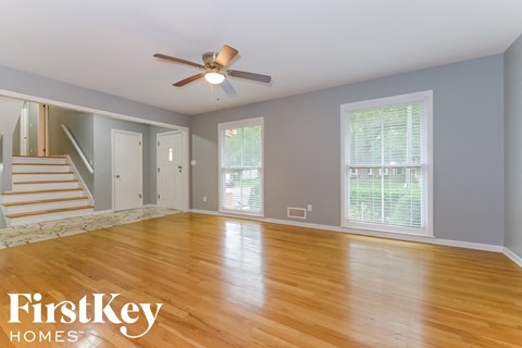 an empty living room with wood floors and a ceiling fan
