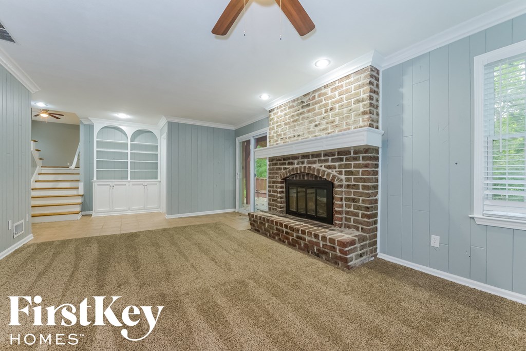 the living room has a brick fireplace and a carpeted floor