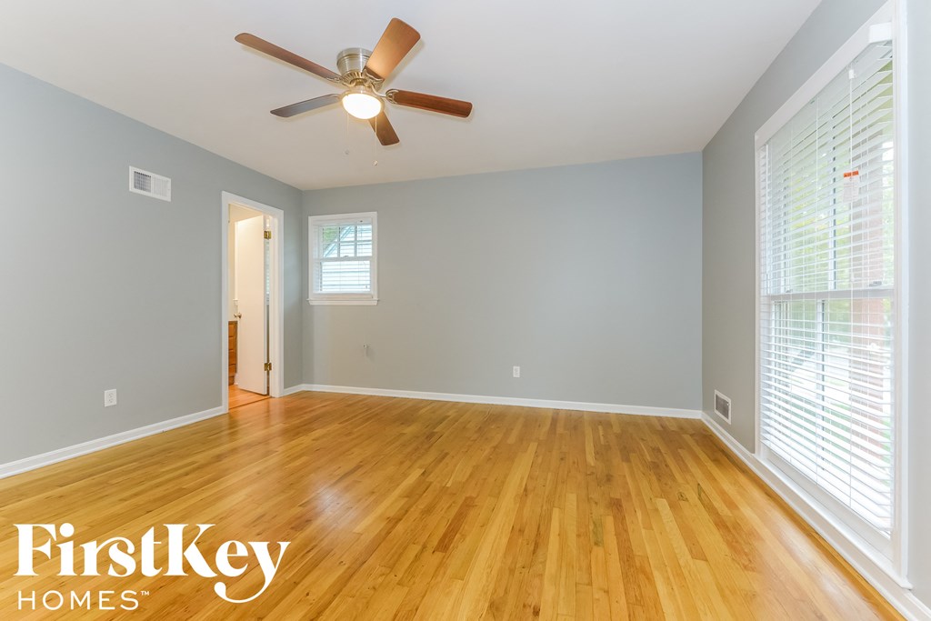 the living room and dining room with wood floors and a ceiling fan