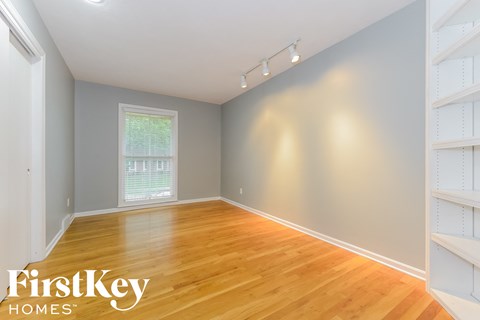 a bedroom with a hardwood floor and a window and white shelves