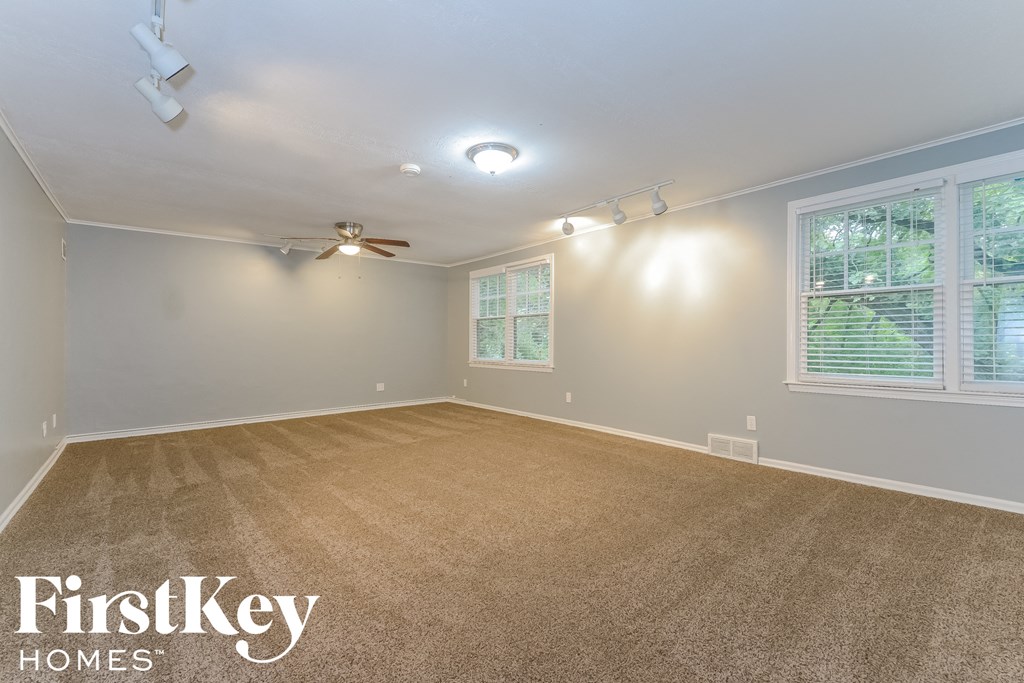 the living room of an empty house with carpet and a ceiling fan