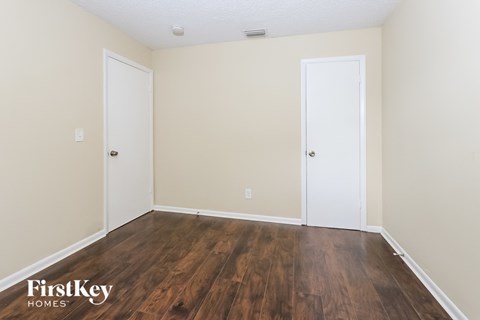 the living room of an apartment with wood flooring and two doors