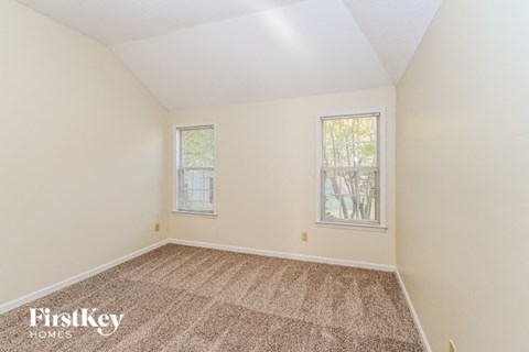 a bedroom with carpet and two windows