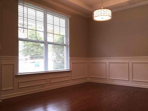 a dining room with a large window and wood floors