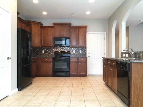 a large kitchen with black appliances and wooden cabinets