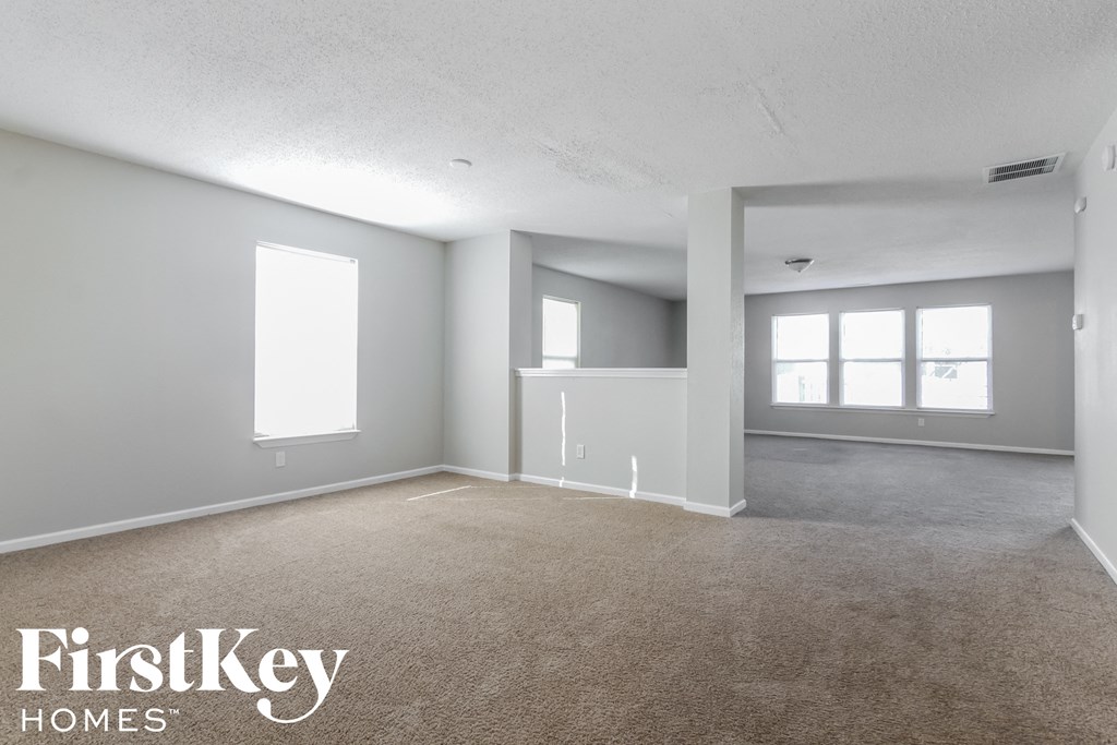 A spacious empty room with a carpeted floor and white walls.
