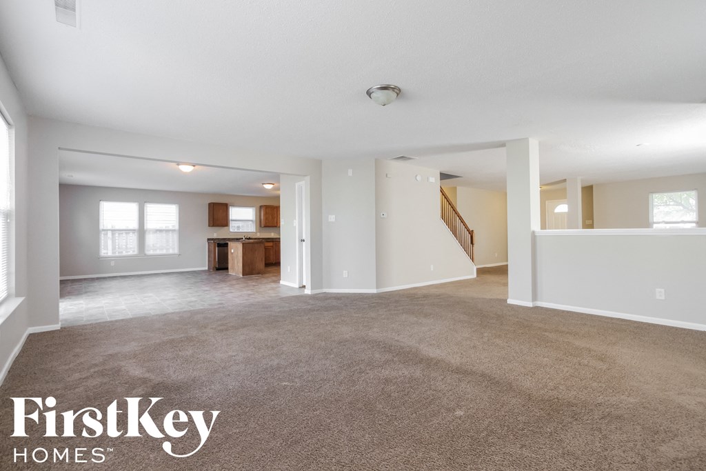 A spacious living room with a carpeted floor and white walls.