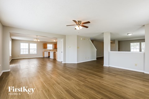 A spacious room with wooden floors and a ceiling fan.