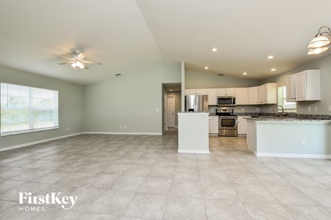 an open kitchen and living room with white cabinets and tile flooring