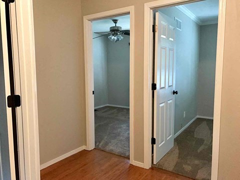 a bedroom with a closet and a door open to a hallway with a ceiling fan