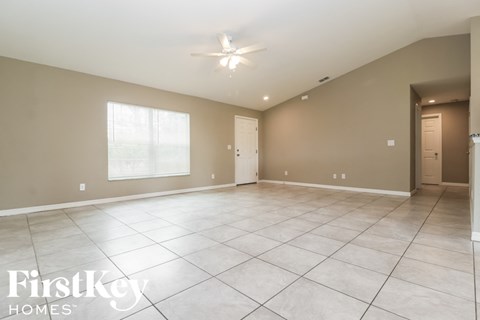 a large living room with tile flooring and a ceiling fan