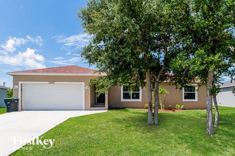 a beige house with a garage and a tree