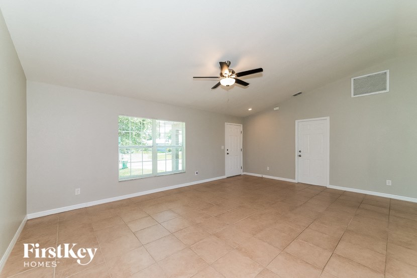 an empty living room with a ceiling fan and a window