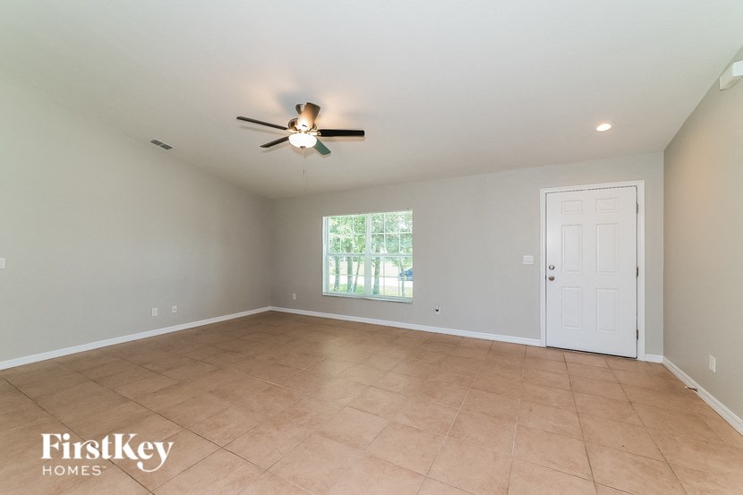 an empty living room with a ceiling fan and a window
