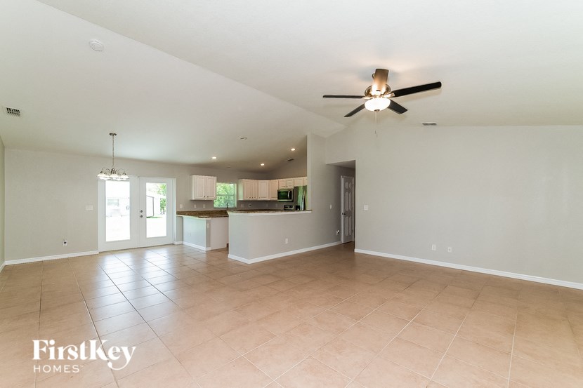 an empty living room and kitchen with a ceiling fan