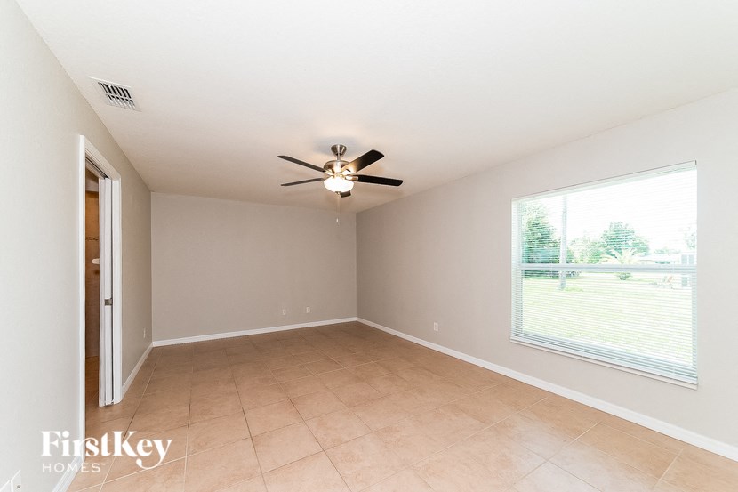 an empty living room with a ceiling fan and a large window