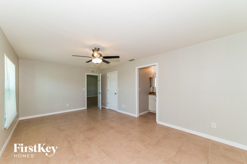 an empty living room with a ceiling fan and tile flooring