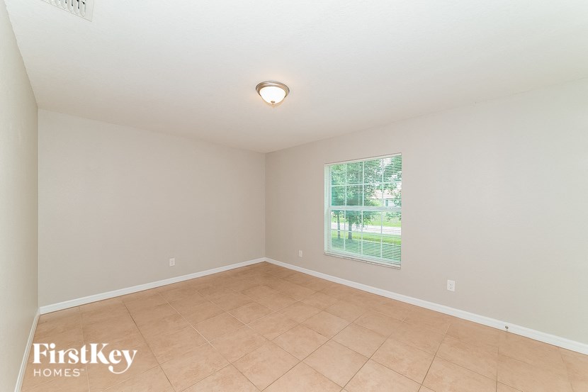 an empty living room with a large window and tiled floors
