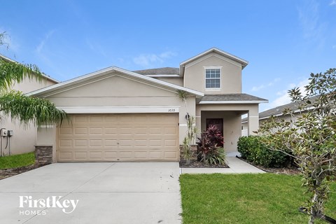 a beige house with a garage door and a lawn