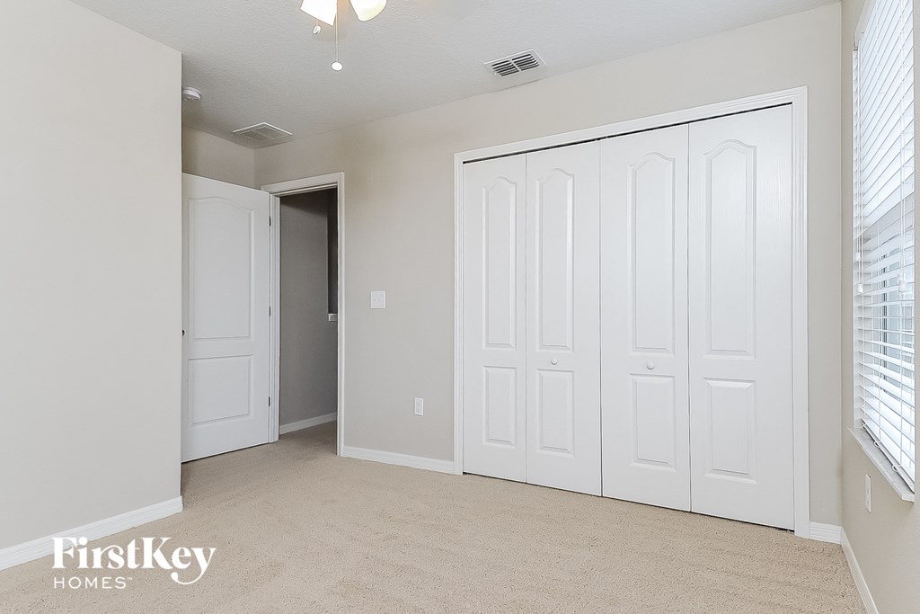 a master bedroom with white closets and a carpeted floor