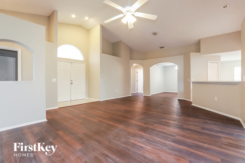 an empty living room with a hard wood floor and a ceiling fan