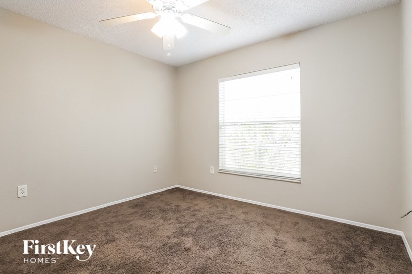 an empty room with a window and a ceiling fan