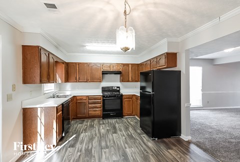 a kitchen with wooden cabinets and a black refrigerator