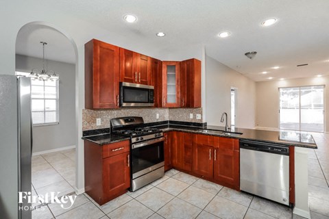 A kitchen with wooden cabinets and a stainless steel refrigerator.