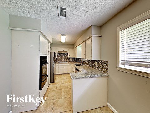 A kitchen with a tile counter top and white cabinets.