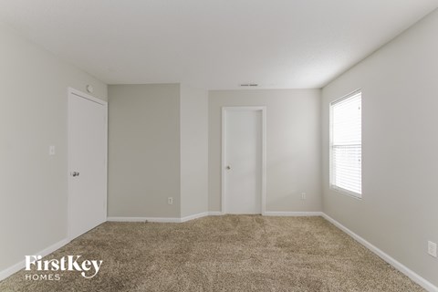 a spacious living room with carpet and white walls