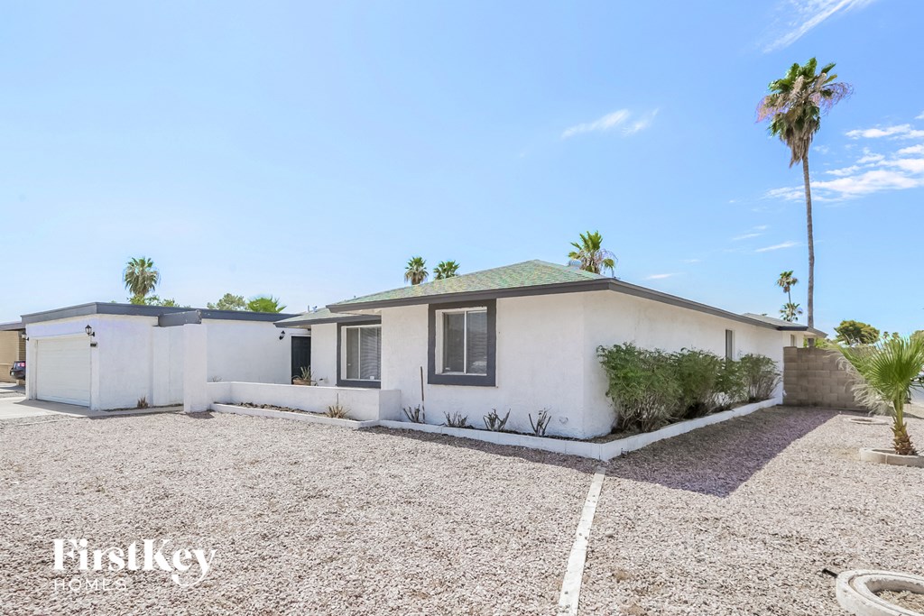 a small white house with a yard and palm trees