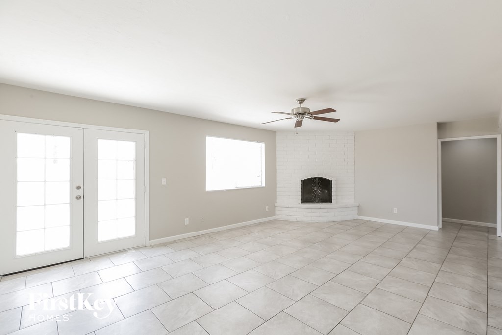 an empty living room with a fireplace and a ceiling fan