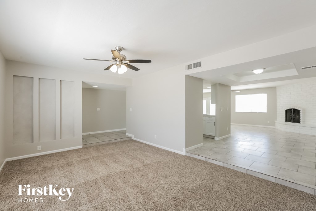 a empty living room with a ceiling fan and a tile floor