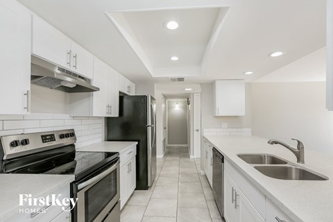a kitchen with white cabinets and black appliances and white counter tops