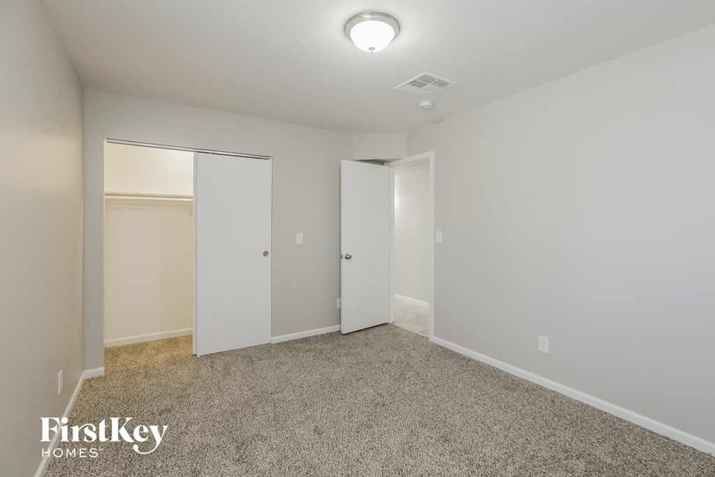 a bedroom with white walls and carpet and a closet