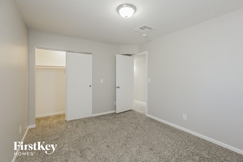 a bedroom with white walls and carpet and a closet