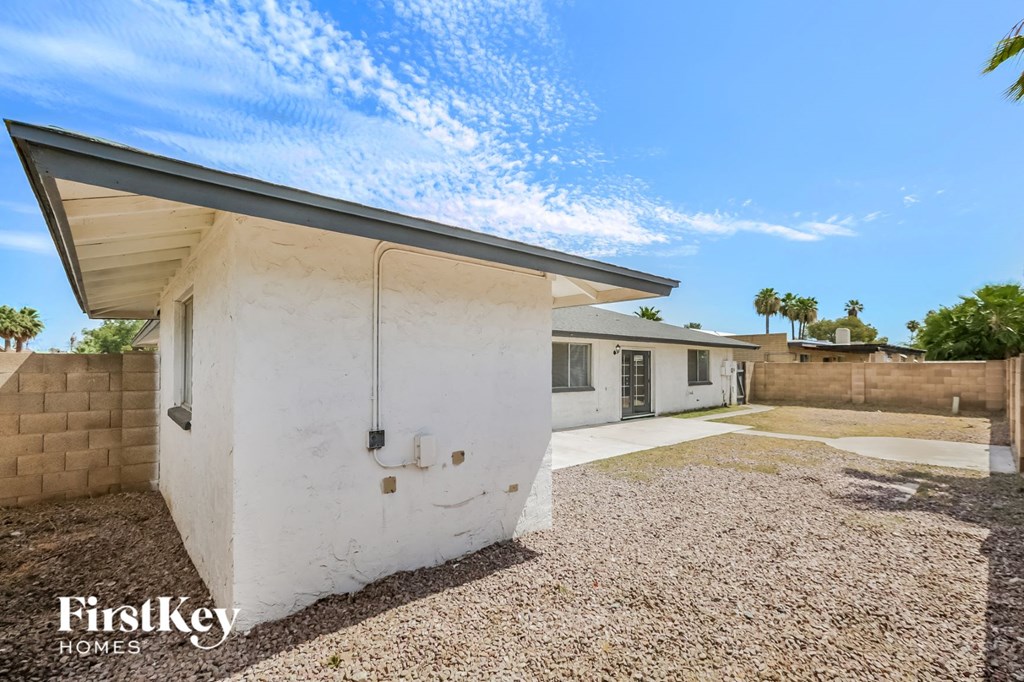 a white house with a garage and a gravel yard