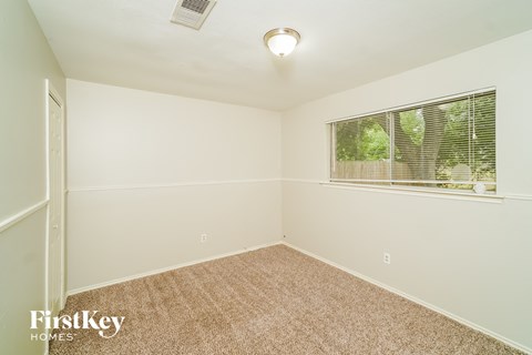 a bedroom with a large window and a carpeted floor