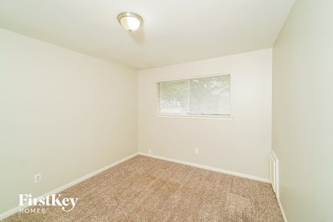 a spacious room with carpet and a window