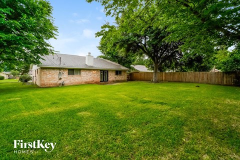 a backyard with green grass and a brick house