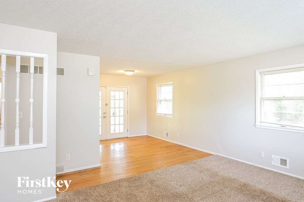 A spacious room with a rug on the floor and a door in the background.