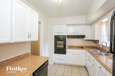 A kitchen with white cabinets and a wooden counter top.