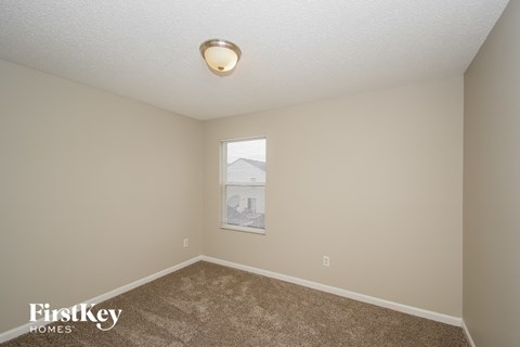 A room with a carpeted floor and a window showing a building outside.