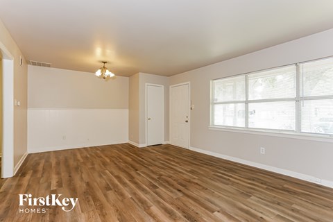 the living room of a home with wood flooring and a large window