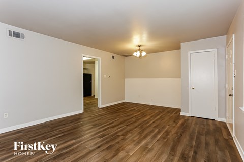 a spacious living room with white walls and wood flooring