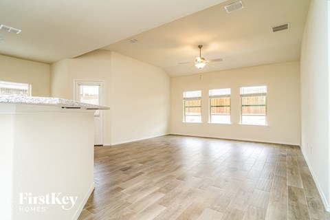 A spacious room with wooden flooring and a ceiling fan.