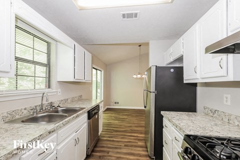 A kitchen with white cabinets and a black refrigerator.