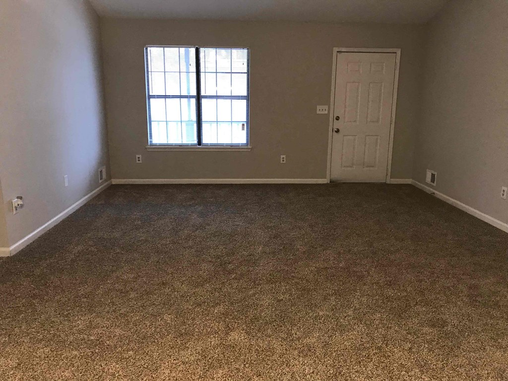 A room with a carpeted floor and a door.